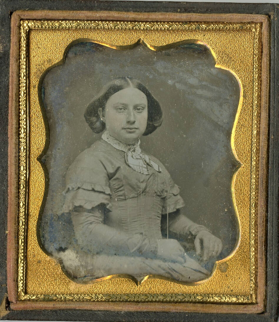 Black and white ambrotype photograph with gold colored frame. Image is of a seated woman.